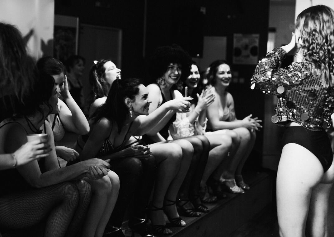 Veselá a podporná atmosféra v tanečnej sále, kde sa ženy spoločne učia umenie zvádzania na kurze burlesque.